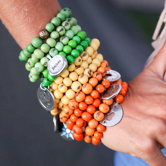 person wearing several acai bracelets wiht blessing rings and wax seals on their arm