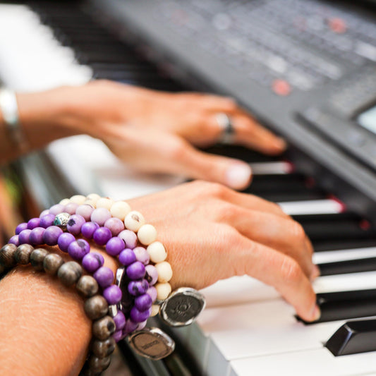 Person wearing bracelets playing an electric piano