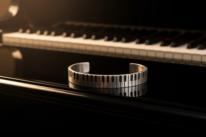 Piano keys cuff bracelet resting on glossy black grand piano body