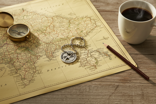 Wanderlust Charm on Map Flat Lay