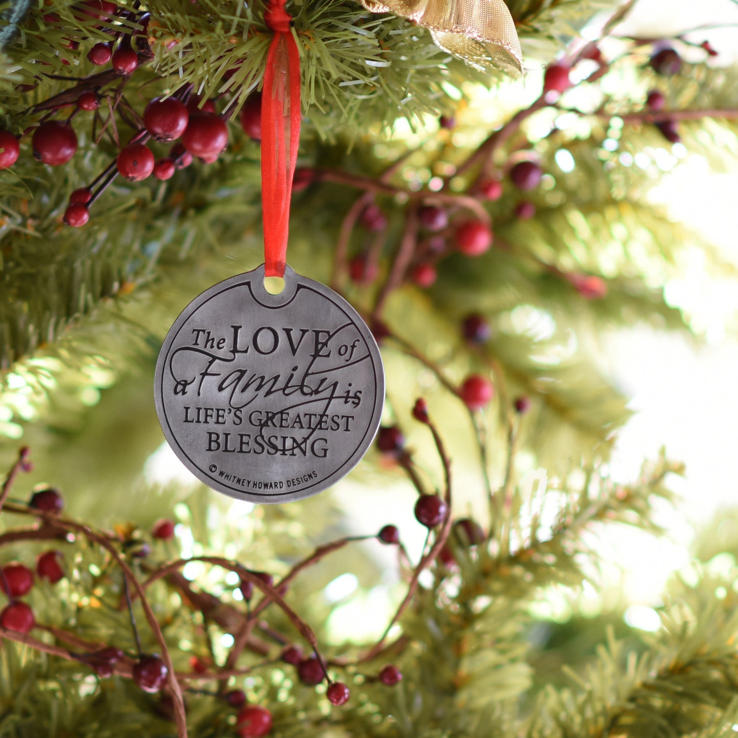 The Love of a Family is Life's Greatest Blessing Holiday Ornament hanging on a tree