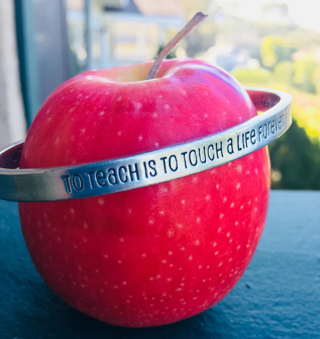 To Teach is to Touch a Life Forever Quotable Cuff Bracelet around an apple