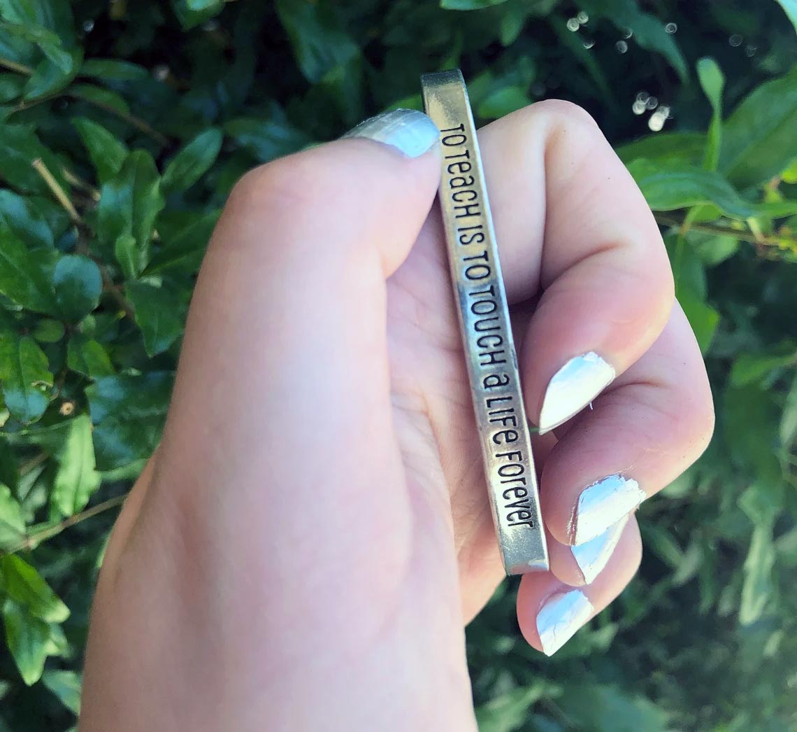 Hand holding To Teach is to Touch a Life Forever Quotable Cuff Bracelet